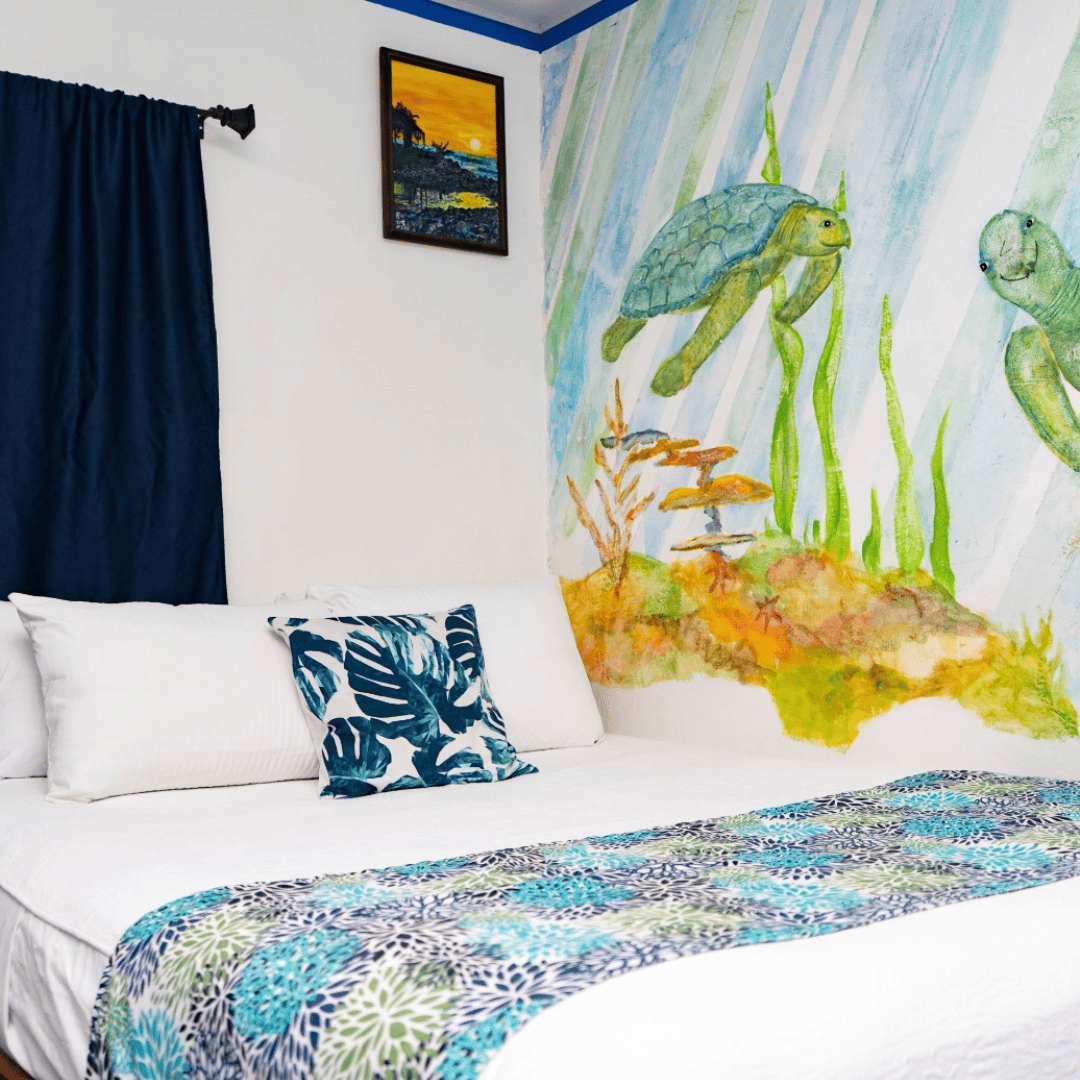 Habitación decorada con mural de tortugas marinas y elementos acuáticos, ambiente relajante y colori.