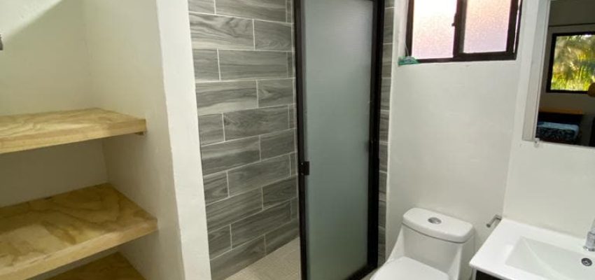 Bañera con ducha y accesorios de baño en un baño moderno con azulejos grises.