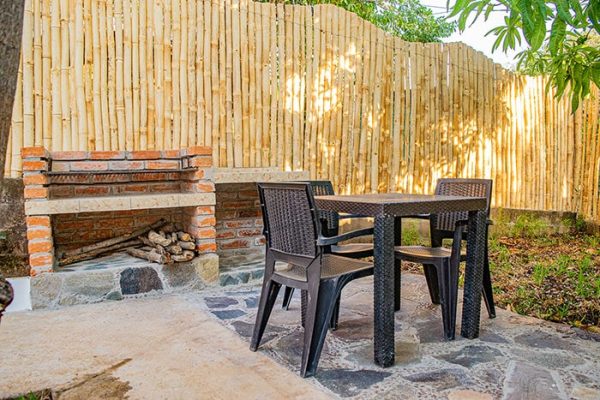Muebles de exterior en zona de jardín con chimenea de madera y madera, ambiente rural y relajante, ideal para disfrutar del verano.