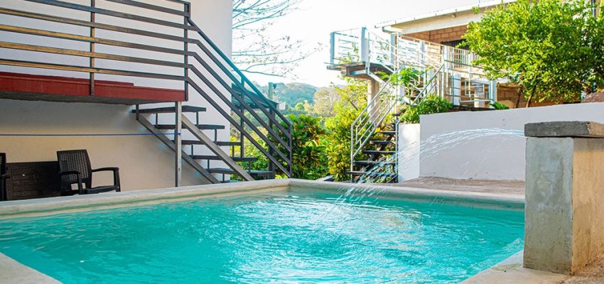 Piscina en alojamiento Olas Permanentes con jardines tropicales y área de relax.