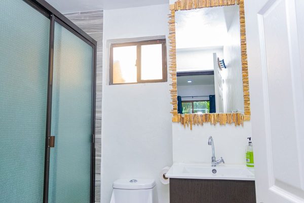 Lámina de espejo decorativo en baño con luz natural y mobiliario moderno.