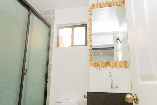 Espejo decorativo en baño con marco de madera, en interior moderna y luminosa, estilo minimalista y funcional.