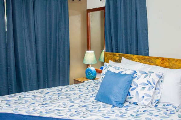 Habitación doble en alojamiento cerca de la playa con ropa de cama en tonos azules y cortinas a juego.