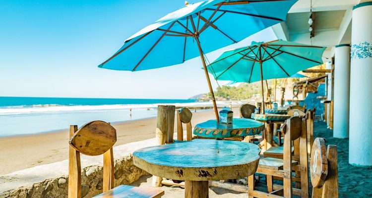 Vacaciones en la playa con sombrillas y terraza frente al mar.