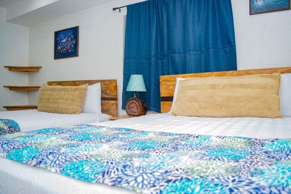 Habitación doble con camas confortables y decoración tropical en Olas Permanentes.