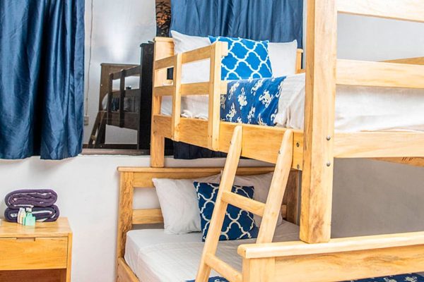 Cómodo dormitorio con literas de madera en alojamiento cerca del mar en La Olas Permanentes, perfecto para surfistas y turistas.