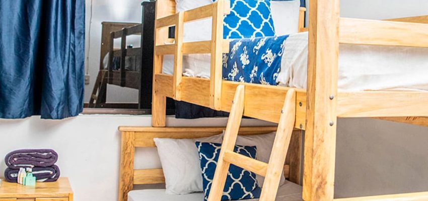 Cómodo dormitorio con literas de madera en alojamiento cerca del mar en La Olas Permanentes, perfecto para surfistas y turistas.