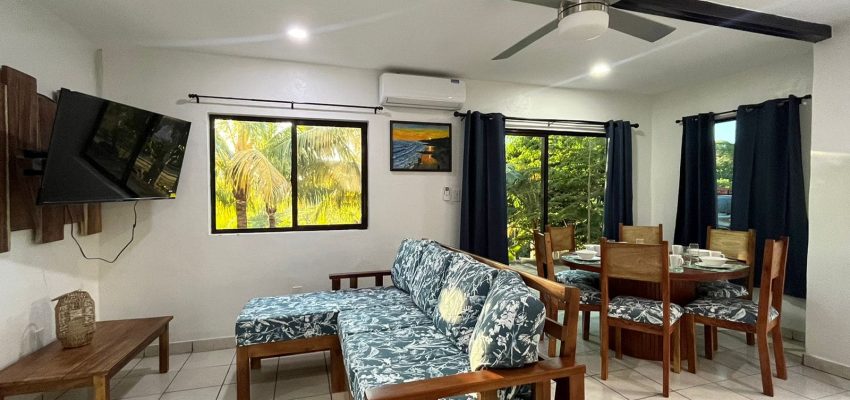 Cómoda sala de estar con comedor y vistas verdes en interior de apartamento.