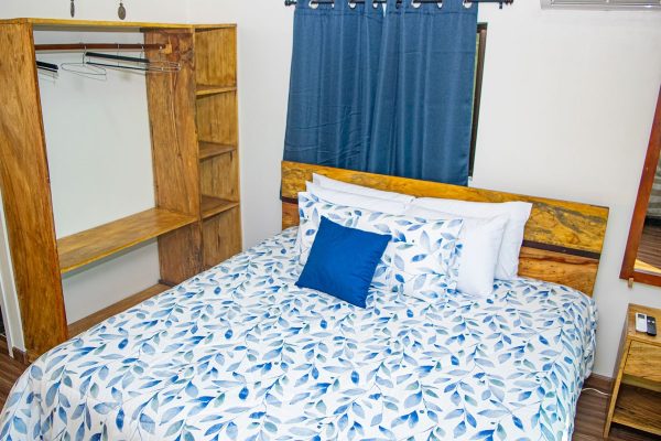 Ropa de cama con diseño de hojas en tonos azules y blancos en habitación de alquiler vacacional.