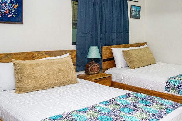 Dormitorio con camas de madera y decoración tropical | Olas Permanentes, alojamiento en surf.